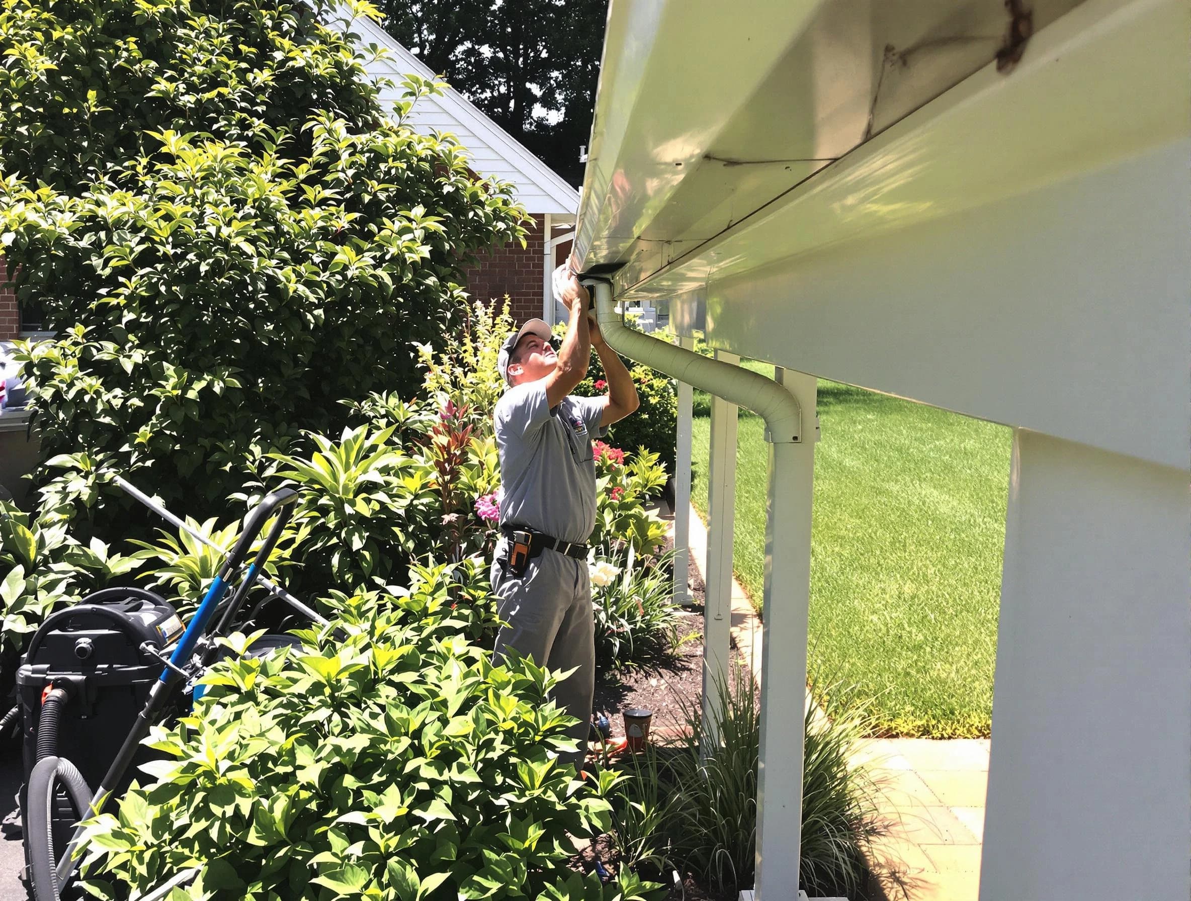 Technician flushing a blockage from a downspout in Aurora, OH